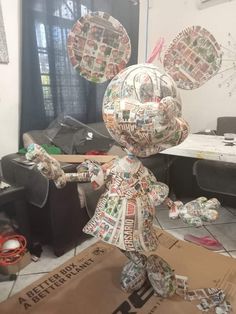 a paper mache doll is standing on top of a cardboard box in the middle of a messy room