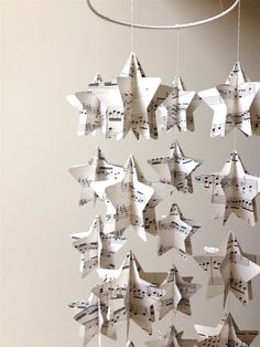 an origami mobile made out of sheet music notes with stars hanging from it