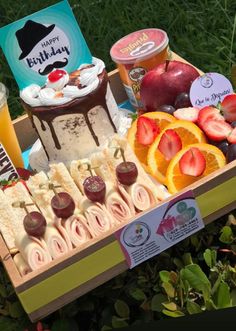 a box filled with lots of food on top of a lush green field covered in grass