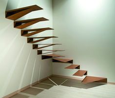 an empty room with a wooden staircase in the center and light coming through it on the wall