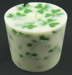 a candle with green leaves on it sitting on a black surface, in front of a dark background