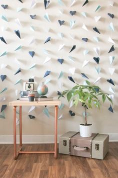 a room with a table, plant and wall hangings on the wall behind it