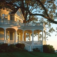 a large white house sitting on the side of a lush green field next to a tree