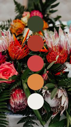 an arrangement of flowers and greenery on a table with color swatches in the middle