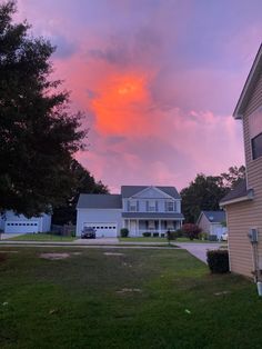 the sky is pink and purple as the sun goes down over some houses in this neighborhood