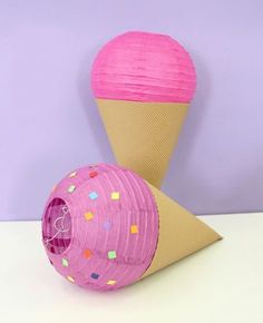 an ice cream cone with pink paper and sprinkles next to it on a table