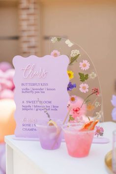 there are two cups with flowers on them and a sign in the background that says, girls butterfly kisses