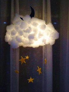 a cloud with stars hanging from it's side in front of a curtained window