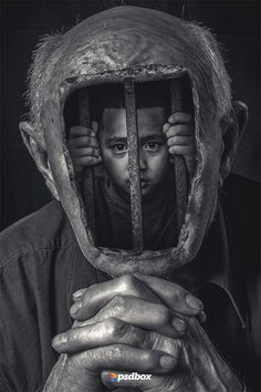 a black and white photo of a man with his hands on his face behind bars