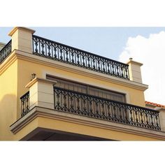 an apartment building with balcony railings and balconies on the upper floor, against a blue sky