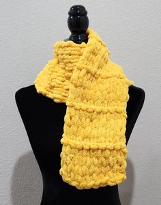 a yellow knitted scarf sitting on top of a mannequin