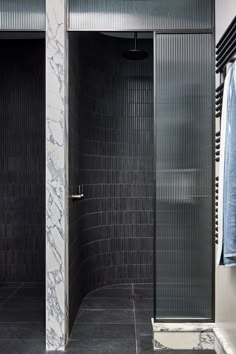 a walk in shower sitting next to a tiled wall