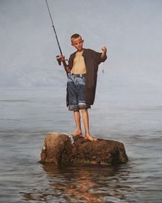 a boy standing on a rock holding a fishing pole