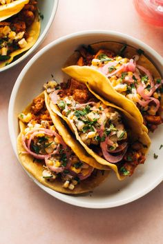 three tacos with meat, onions and cilantro on a white plate