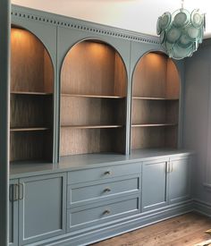 an empty room with blue painted cabinets and wood flooring, along with a chandelier hanging from the ceiling