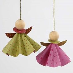 two paper angel ornaments hanging from strings on a white background with polka dotes and dots