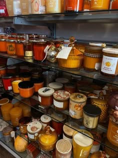 shelves filled with lots of different types of jars and sauces on display in a store