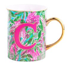 a pink and green coffee mug with the letter c on it's side, decorated with tropical leaves