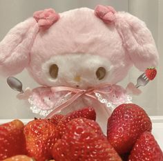 a pink stuffed animal sitting next to strawberries