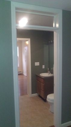 an open door leading to a bathroom with a toilet and sink in it's center