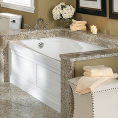 a bathroom with marble counter tops and bathtub in the corner, surrounded by framed pictures on the wall