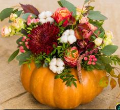 a pumpkin filled with lots of flowers on top of a table