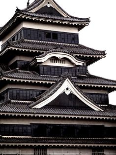 a tall building with black and white roof tiles on it's sides, in front of a cloudy sky