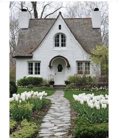 a white house with tulips in the front yard and walkway leading to it