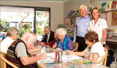 a group of older people sitting around a table with crayons in front of them