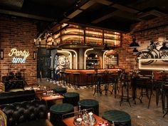 the interior of a bar with lots of tables and chairs in front of brick walls