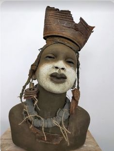 a clay head with white and brown paint on it's face, wearing a hat