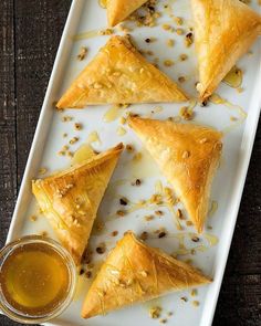 several pastries on a white plate with mustard and seasoning next to each other