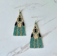 two pairs of beaded earrings with black and green beads on white marble counter top