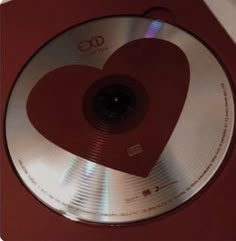 a cd with a heart on it sitting on top of a red table next to a white wall