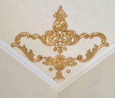 the corner of a ceiling with gold decorations on it's sides and a white wall in the background