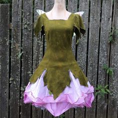 a green dress with pink and white flowers on the skirt is displayed in front of a wooden fence