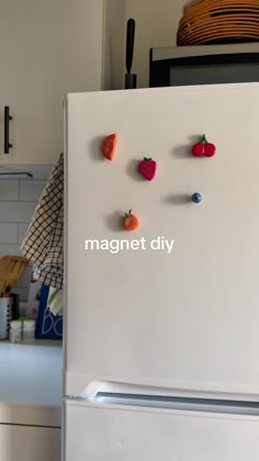 magnets are attached to the side of a refrigerator in a kitchen with white cabinets