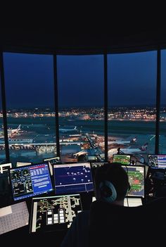 a man sitting at a control desk in front of a window looking out on the ocean