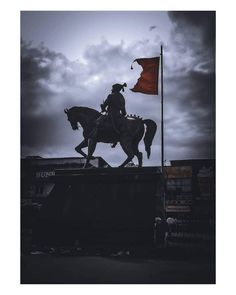 a statue of a man riding on the back of a horse next to a red flag