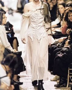 a woman walking down a runway with lots of people in the background