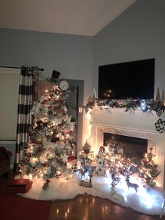 a decorated christmas tree in front of a fireplace with lights on it and a tv above