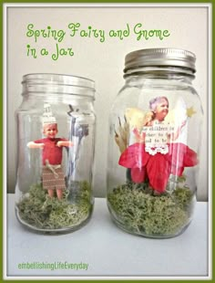 two glass jars filled with moss and little figurines