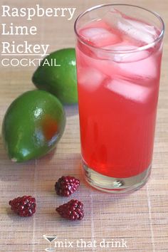 a drink with raspberries and limes next to it