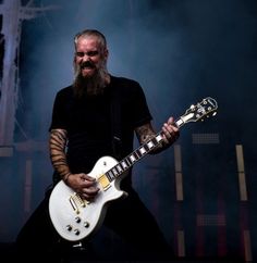 a man with long hair and beard playing an electric guitar