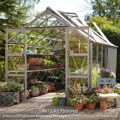 a small greenhouse with lots of potted plants and flowers in the ground next to it