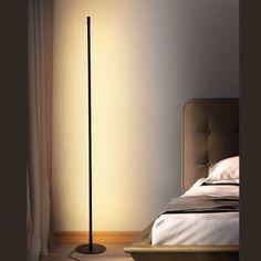 a bed sitting next to a lamp on top of a wooden floor