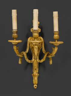 an antique wall light with three candles on it