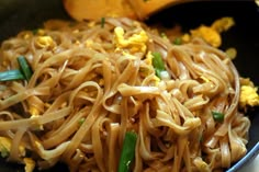 noodles and vegetables are being cooked in a wok