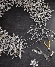 a bunch of beads and scissors on top of a piece of black paper with snowflakes