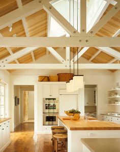 an open kitchen with wooden floors and white walls, along with wood beams on the ceiling